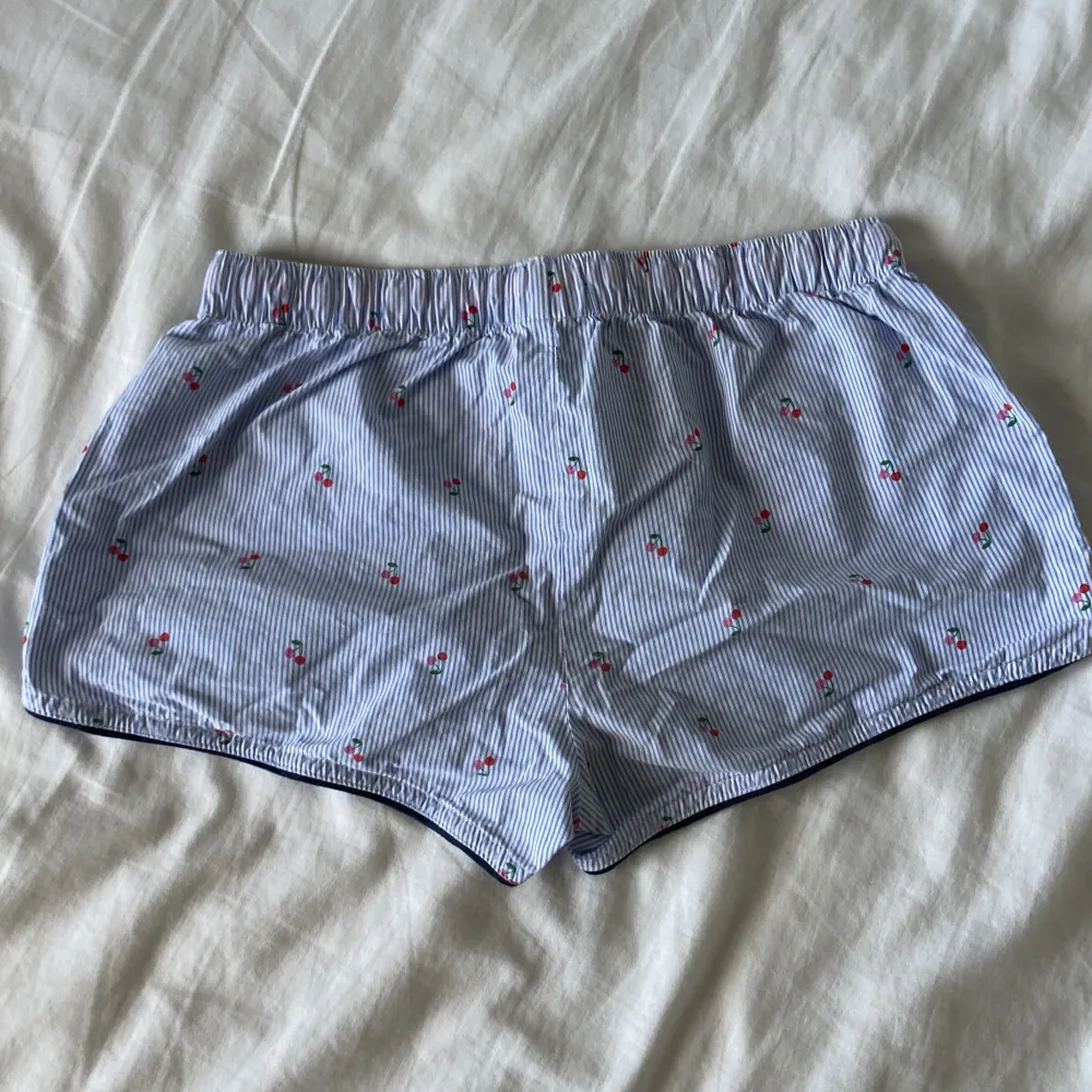  Super söta vit/blå randiga lågmidjade shorts med små körsbär🍒🍒 Passar perfekt som pyjamas shorts men är även jättesnygga att ha nu till sommaren!🌸 köpta från Holly & Whyte!. Shorts.