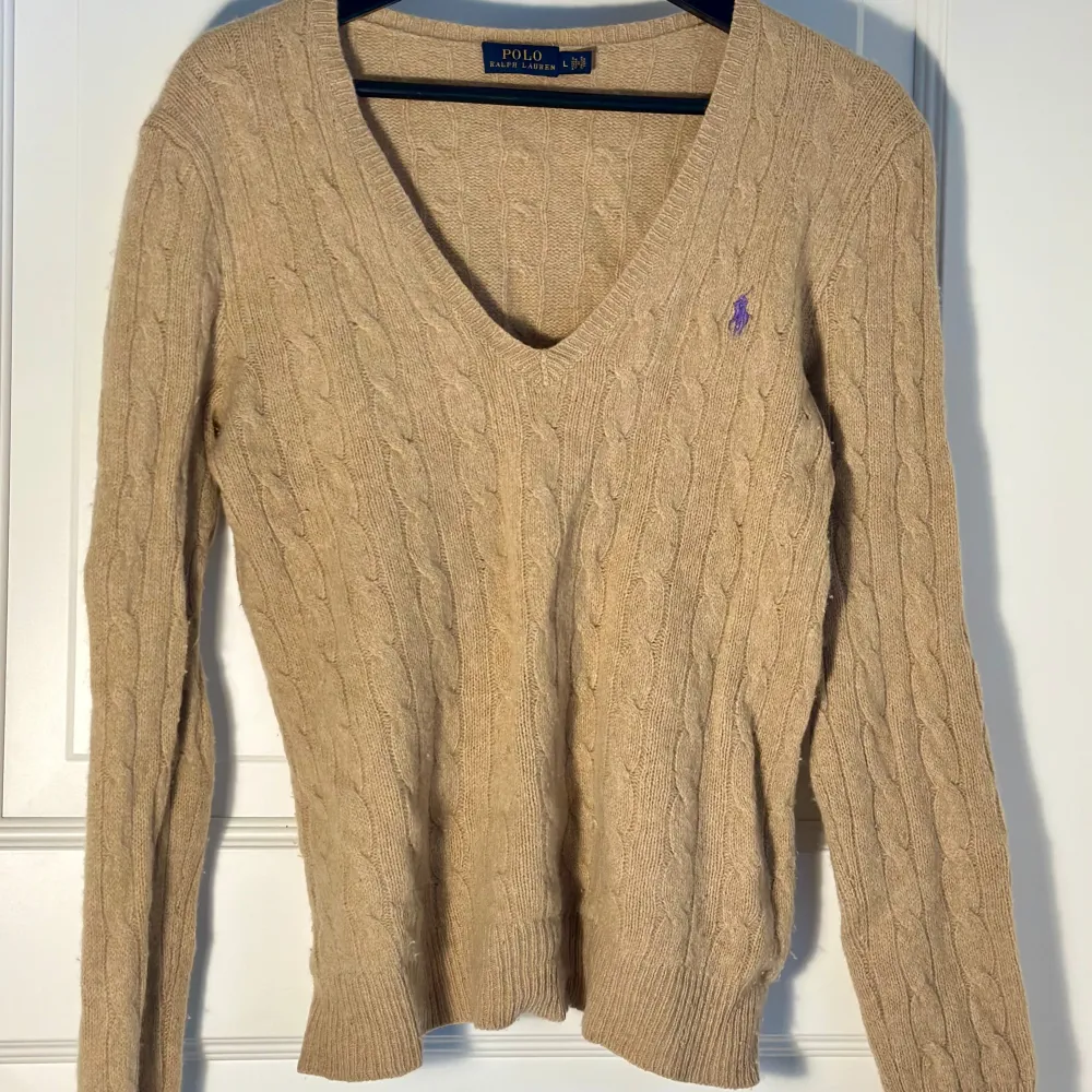 Klassisk kabelstickad tröja från märket Ralph lauren. Färgen är Camel Melange och storleken är L (för barn). Sitter snyggt och tight på mig som har vuxen storlek M i vanliga fall. Tröjan är tillverkad i bomull och nypris är omkring 2400kr. . Hoodies.