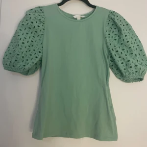 Grön tröja med puff ärmar - En grön tröja från HM med puffärmar. Prislappen sitter kvar och tröjan är aldrig använd. Originellt köpt för 149 kr men säljs för 49