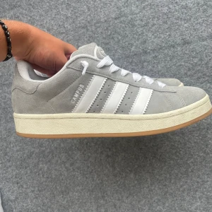 Adidas campus 00s - Jag säljer mina adidas campus 00s i mycket fint skick då de endast är använda ett fåtal gånger😁. Storlek 43 och 1/3 men passar mig som har 42-43 och säljes pågrund av att de ej används. Riktigt snygga skor i bra kvalite🔥. Extra skosnöre finns med  