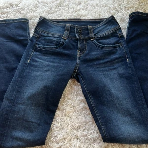 Mörkblå jeans från Pepe Jeans - Ett par mörkblå jeans från Pepe Jeans i storlek W10. Byxorna har en rak passform. De har klassiska fem fickor och dekorativa sömmar på bakfickorna.                                                                                     Jeansen är knappt använda, säljer då de inte kommer till användning. 