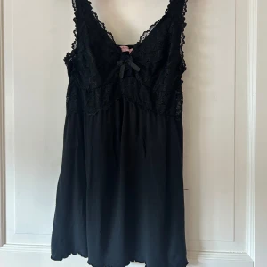 Svart klänning från Hunkemöller - svart långt linne / babydoll/ mini klänning med spets och rosett  från hunkenmöller i storlek s. plagget är 50cm från rosetten till botten av klänningen, har justerbara axelband. jättefint skick, möjligen små lösa trådar som ej syns