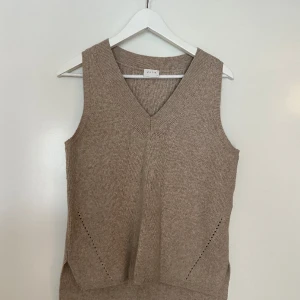 Stickad väst - Beige stickad väst från VILA med fina detaljer, V-form och ”slits” på sidorna. Storlek XS men funkar som S.