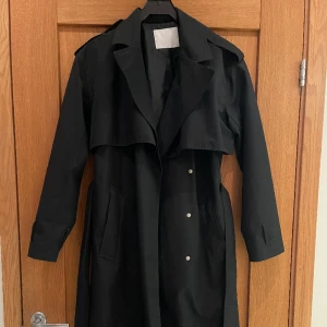 Så snygg trenchcoat  - Skitsnygg svart trenchcoat, perfekt nu till våren. Storlek xs men passar allt från xxs-m.