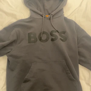 BOSS - Luvtröja - Mörk Grå - säljer min BOSS hoodie då jag ej ser att jag använder den längre. Varan är i fint skick och köptes för ungefär ett halv år sedan. Använd ett par fåtal gånger.  Kvitto finns på köpet och vid snabb affär kan jag gå ner i pris! Nypris ligger på 1225. 