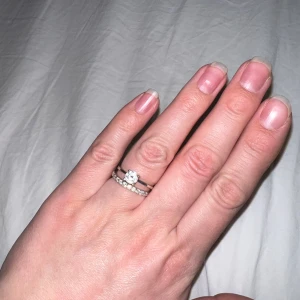 Ring i äkta silver - Två ringar i äkta silver med kubisk zirkonia. Den ena ringen har en större sten med kubisk zirkonia, medan den andra ringen är en alliansring med flera mindre stenar.