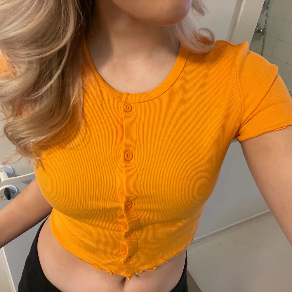 Orange crop top med knappar strl M. T-shirts.