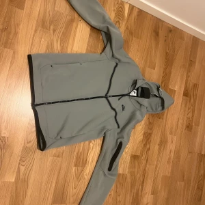 Nike tech  - Hej jag säljer en Nike tech kofta. Storlek S, grön/grå. Koftan säljs pga den är förstod och inte används mer, köpt för ett år sen ungefär för 1300kr men säljs för 750kr