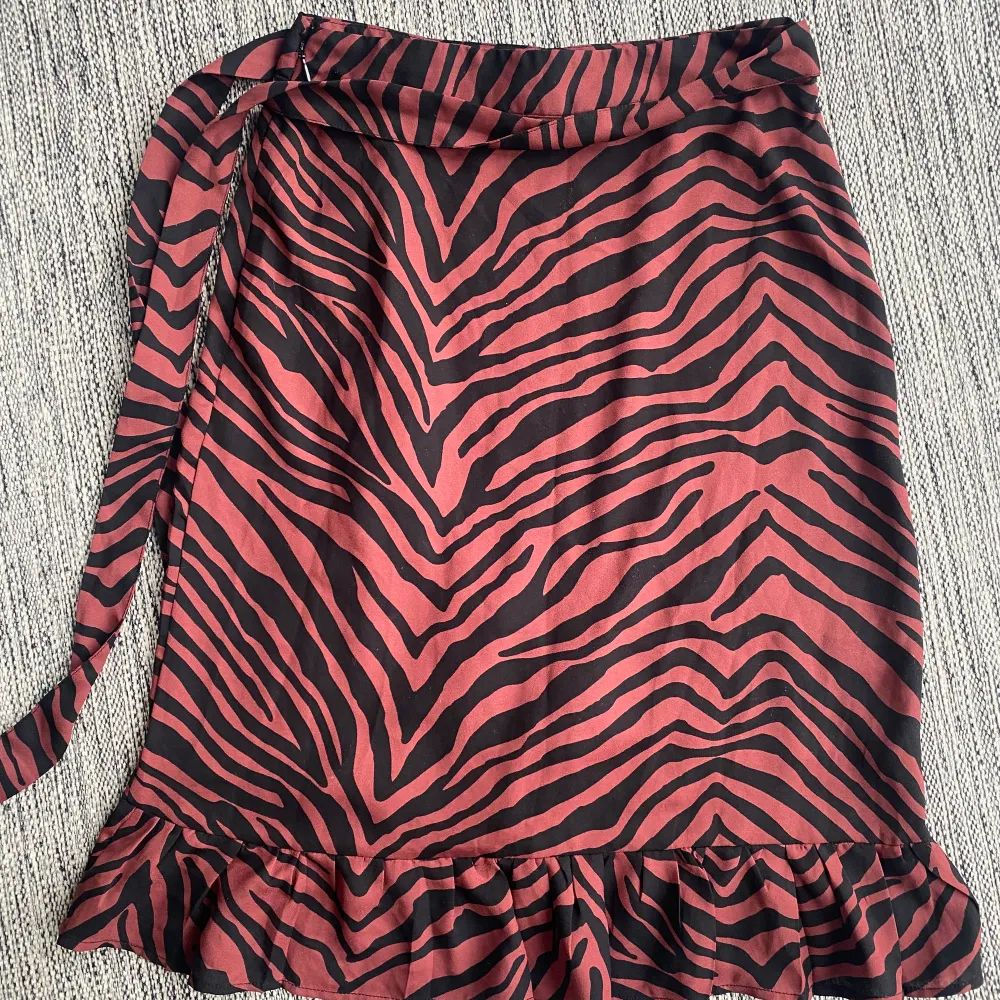 Svart och röd omlott kjol i leopardmönster i strl xs.  Förutom en liten tråd se bild 2 är kjolen i fint begagnat skick då den endast använts en gång.  Mått Midjan: ca 32 cm Total längd: ca 60 cm. Kjolar.