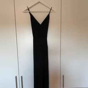 Svart byxdress - Svart byxdress med långa & vida ben i storlek XS från Bikbok. Öppen i ryggen då banden är väldigt tunna, v-ringad framtill