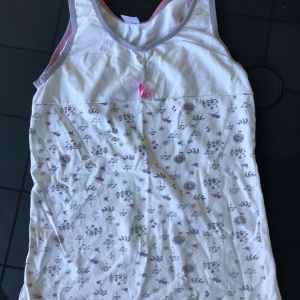 Linne - Fint linne med Blommönster och en rosett. Bak är den hel vit. Väldig skön och storleken sår inte men ungefär 134/140.