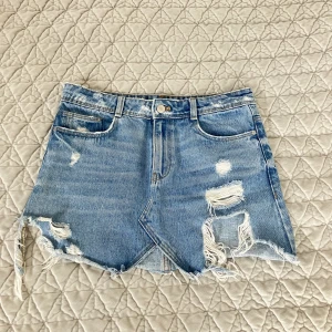 Jeanskjol - Så snygg jeanskjol, coola slitna detaljer på!  Midja: 38 cm