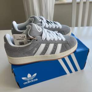 Gråa Adidas Campus 00s. Helt oanvända med prislapp kvar, samt box. Strl 39 1/3. Originalpris 1299.