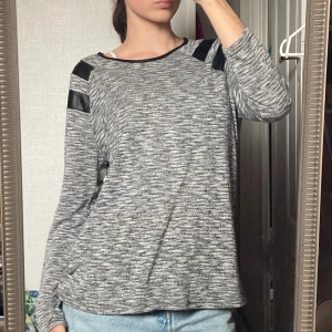 Tröja - Cool långärmad grå tröja med svarta läder straps på axlarna🫶🏼 Man kan även ha den lite off shoulder🫶🏼 passar alla storlekar beroende på hur man vill att den ska sitta själv så har jag storlek S för referens.