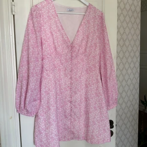 Klänning - Supersöt miniklänning i ett ljusrosa tyg med vita små blommor på. Helt oanvänd, storlek 40