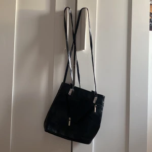 Väska - Handväska som går att ha på flera sätt baserat på hur du knäpper banden. Gjord i Italien, svart. Banden är något slitna men annars i fint skick!💗