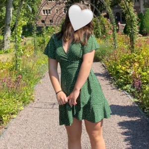 Klänning - Supersöt grön klänning med vita prickar. Det är en omlottklänning och knyts alltså ihop med ett band som man knyter vid sidan. 