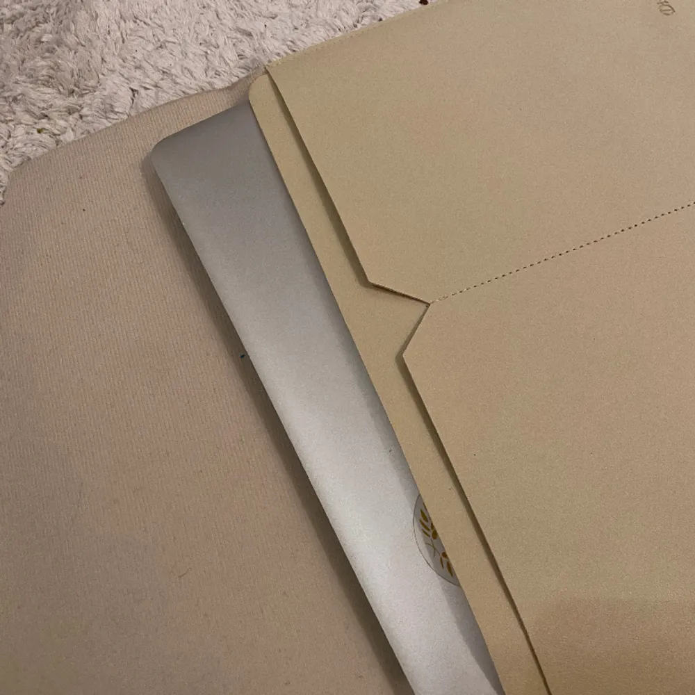 Datorfodral i beige med två extra fickor. Några svarta sminkmärken på den som man ser på bilden men går nog bort med lite fläckborttagning.. Laukut & Käsilaukut.