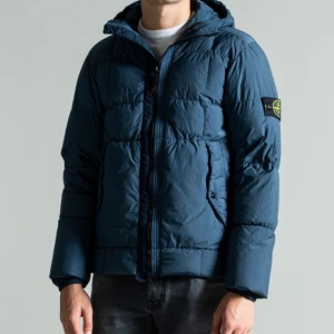 Stone Island Down Jacket  - Använd i ett år, god som nyskick  Storlek: Large Nypris: Ca 8000kr.Säljs pga att jag köpt ny jacka och denna ej används längre. Använde jackan för ungefär 2 år sedan. Jackan anpassar sig till vädret då den är luftig samt varm, perfekt för vinter/höst. OBS: Ett litet märke finns på övre axel. Se sista bild. Märket syns inte när man har på jackan och det är väldigt litet(ser större ut på bild).