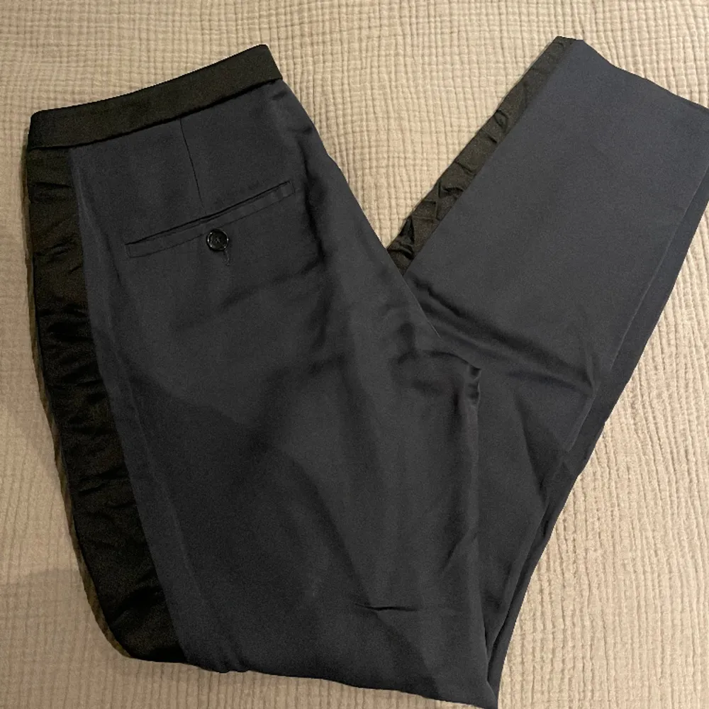 Kostymbyxa i silke från Dagmar! Super fina och lyxig kvalite. Straight i modellen och mindre i storleken. Mörkblå med svarta sido ”stripes”💙. Jeans & Byxor.