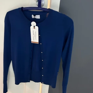 Cardigan - Cardigan från Holly&White aldrig använd etiketten kvar, guld knappar. Normal i storlek.