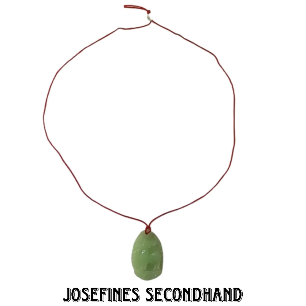 Halsband med jade sten och rött snöre med motiv av en get. Har liten jade sten som används för att justera storleken på halsbandet. Skickas med brev, frakt blir 15 kr. Gratis frakt vid köp av 3 eller fler accessoarer/smycken/sminkprylar. Ej äkta jade. Accessoarer.
