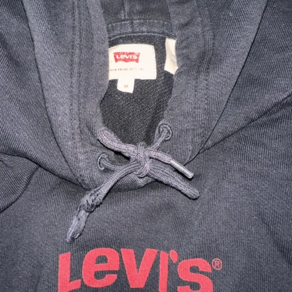 Svart Levi’s hoodie i storlek M. Bra skick men har slitning på snöret som syns på sista bilden.. Hoodies.