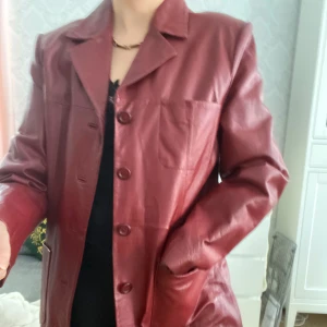 Läderkappa vintage  - Vinröd läderkappa från 90-talet i gott vintage skick   Liten skada vid ena ärmen i innerfodret Fullång Storlek 40 så passar nog bra på en 38 