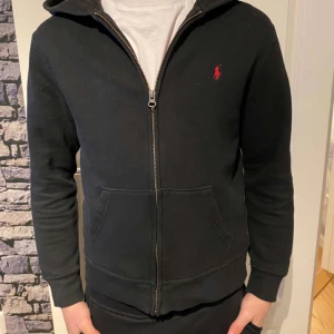 Polo Ralph Lauren zip - Jag säljer min polo Ralph lauren zip Hoodie på grund av att den har blivit förliten. Inga skador den är väll använd men bra skick.  Fråga om det är några frågor eller om du vill ha flera bilder. Pris kan diskuteras. 