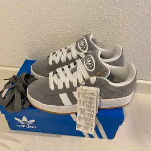 Nya grå Adidas Campus 00s -storlek 36 2/3 - Adidas Originals Campus 00 s j Storlek: 36 2/3 Färg: Grå (Grey Three / Cloud White / Cloud White).  Ingår både vita och gråa skosnören. Nya och oanvända. Ligger kvar i kartong. Kommer EJ från någon massbeställning utomlands. 100% äkta. Sista paret!