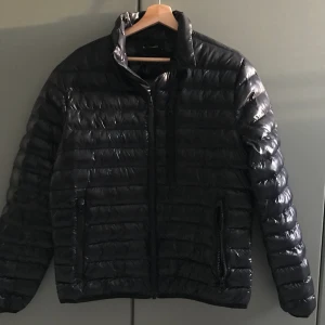 Svart peak performance jacka - En svart och glansig peak performance dunjacka för lite kallare temperaturer, Nyskick.