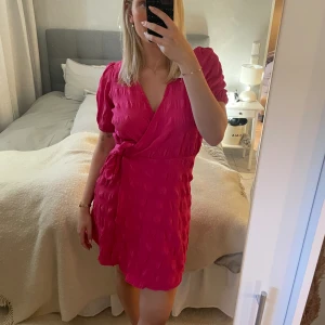 Rosa omlottklänning - Rosa omlottklänning, aldrig använd med lappen kvar. Passar perfekt till sommaren!