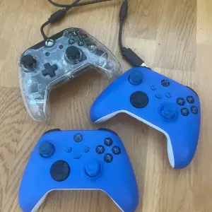 3 stycken Xbox controller. De två blåa är trådlösa Xbox controller till för Xbox series. Men funkar även till Xbox one. Den andra som är genomskinlig är inte äkta och den är med sladd.