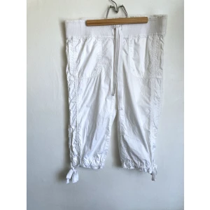 Vita capribyxor, 32 XXS, bomull, somriga, vit, trekvarts, y2k - Capribyxor i vit bomull, bred mudd med dragsko i midjan, dragskor i bensluten, råa benslut. Finns lösa trådar i sömmarna. Mått får ej plats - fråga gärna!