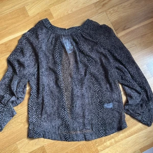 Orm prinnt skir blus - Skir blus med långa ärmar , knapp på baksidan upp och nere, öppning i ryggen, lätt genomskinlig helt ny prislappen på 