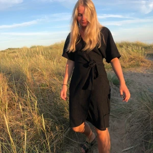 Svart klänning - Jag säljer min svarta omlottklänning som är i storlek xs. En fin och enkel sommarklänning som är enkel att klä upp och ner🥰