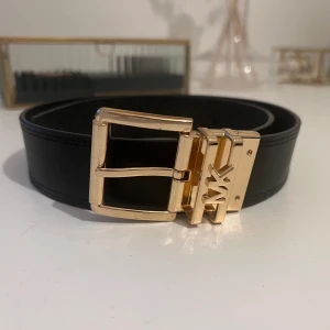 Michael Kors bälte - Äkta Michael Kors reversibel belt. Skärpet är i 100% skinn och kommer i storlek XS (80 cm). Skärpet har två olika sidor, ena sidan är helt svart och andra sidan har MK tryck. Ett väldigt fint bälte i hög kvalitet, går att styla på många olika sätt. 