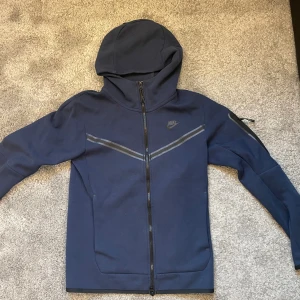 Nike tech fleece  - Snygg Nike tech fleece marinblå färg, storlek XS modellen på bilden är 1,70cm, bra skick ända defekten är på den övre dragkedjan (bild 5)  Hör av dig om du har frågor! 