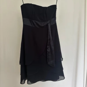 axelbandslös volangklänning  - svart ärmlös klänning från marie blanc. står ingen storlek men skulle säga att den passar XS-S. den har ett band längs bysten så att den håller uppe bra. dragkedja längs sidan