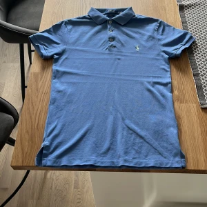 Blå raffe pike - skön piké från Ralph louren med skön färg passar as bra till detmästa och är knappt andvänd men säljer för den börjar bli för liten den är mellan s och m så skriv vid minsta fundering