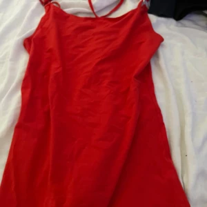 Röd klänning  - En röd klänning med ”detaljer” på ryggen  ( köparen står för frakt)