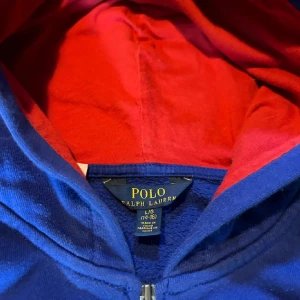 BLÅ RALPH LAUREN HOODIE  - Det är en blå Ralph Lauren Hoodie med zip i ett skick av 7/10. Det passar en på ungefär 170 cm med storlek L (14-16)