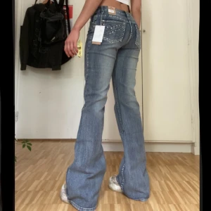 Lågmidjade jeans m rhinestones - Suuupersnygga lågmidjade jeans från Bonnygirl. Rhinestonedetaljer på fickorna både fram och bak! Bootcut modell. Nyskick med lapparna kvar. Skriv om du har frågor eller vill ha fler bilder