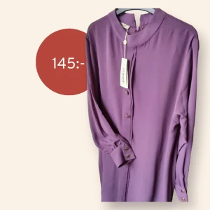 Snygg lila skjorta med guldiga knappar - Lila skjorta i Nyskick. Aldrig använd, lapp kvar   Snygg lila skjorta med guldiga knappar