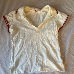 kvinnlig pikétröja  - En vit pikétröja med rött på kanten. Näst intill aldrig använd. 