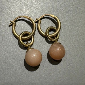 WOS örhängen  - Coola örhängen i guld från WOS. Aldrig använda🩷🩷 en ljusrosa/beige pärla/sten