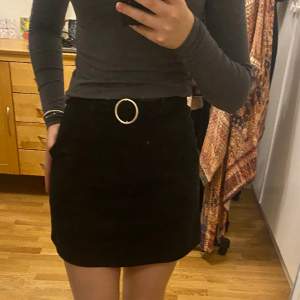 En kort svart kjol med inbyggt skärp och fickor