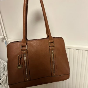Väska - Brun handväska i bra skick! Rymlig inuti med olika fack och dator får plats! Skriv för mer info/ bilder / prisförslag🫶