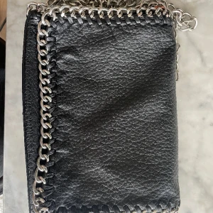 Tiamo väska svart  - Tiamo väska svart i bra skick! Mått: Längd 28 cm, höjd 18 cm, bredd 5 cm.