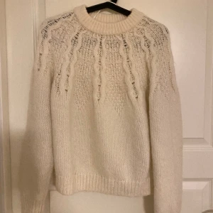 STICKAD TRÖJA - Vit stickad tröja, perfekt att slänga på sig över klänningen en sommarkväll. Fint mönster. Man kan ha ett linne eller annan beige tröja under om man vill täcka hålen. Jättefin och skön. Köpt för 400kr säljer nu för 190kr. Oversize passform.